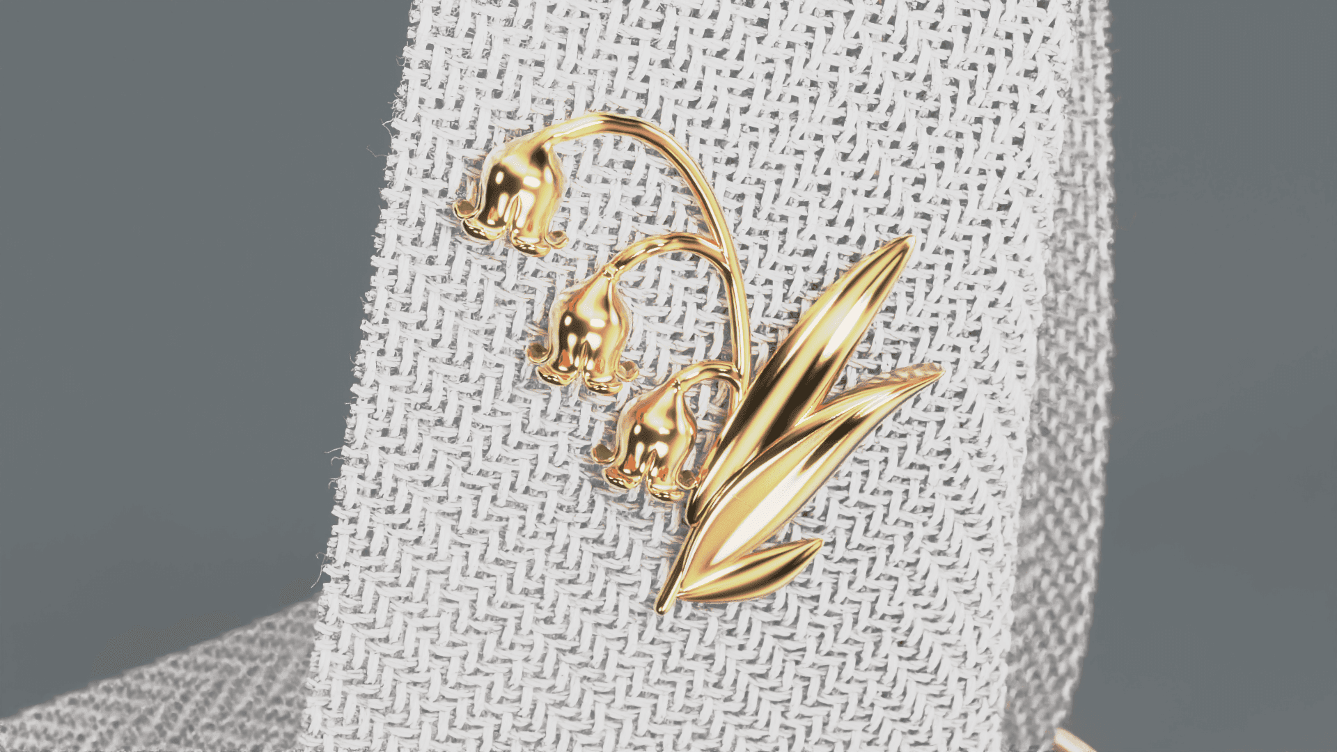 Gold lily of the valley pin on a textured gray fabric background.